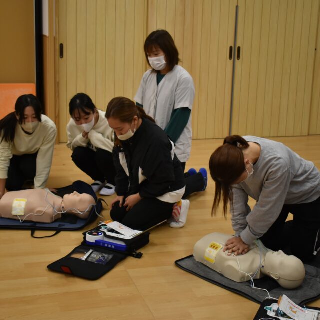 🫀命を守る研修を行いました11月22日に、日本ライフライン(株)から講師をお迎えし、心肺蘇生法とAEDの研修を実施しました。今回は映像での学びに加え、人形を使った実践的な訓練を実施しました。「反応のない傷病者」を発見した時の初動対応から、AEDを用いた電気ショック（除細動） まで、一連の流れを確認しました。班に分かれての実習では、「心肺蘇生（胸骨圧迫）を絶やさない」 連携の重要性を学びました。疲れで圧迫の質が落ちないよう、タイミングよく次の人に代わる方法も実践。「誰か代わってください！1、2、3！お願いします！」と連携の練習も行いました。また、窒息時の異物除去についても、乳幼児の身体的特徴を考慮した方法を教えていただきました。日常から事故防止に努めることはもちろん、「万が一」に備え、全職員が真剣に技術と心構えを学びました。#わかば保育園 #大阪市 #生野区 #社会福祉法人 #認可保育園 #園内研修 #心肺蘇生法 #AED研修#子どもの安全 #救命講習 #安全管理